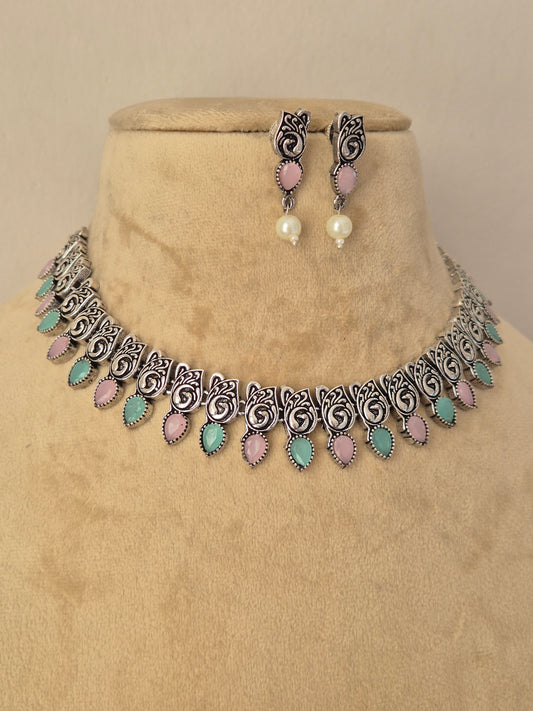 Pair of oxidized silver floral motif necklace featuring light blue stones paired with matching drop earrings by naitri.in