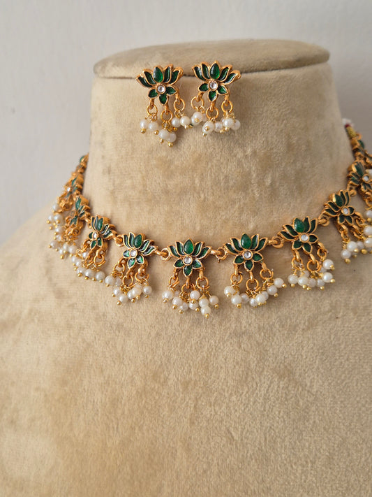 Antique gold-plated Indian ethnic choker set featuring green enamel floral motifs, delicate dangling white pearls, and a matching pair of stud earrings by naitri.in