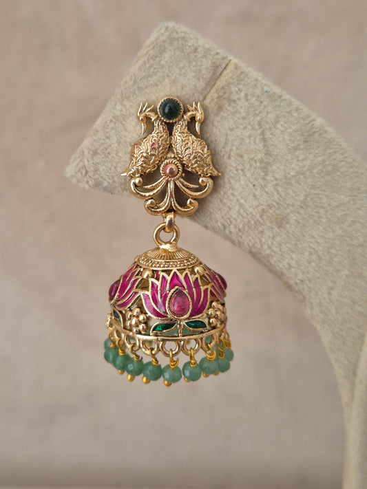 Close-up of Naitri Manorama premium gold ethnic earrings showcasing traditional Indian temple jewelry craftsmanship with vibrant pink and green enamel work and dangling green beads by naitri.in