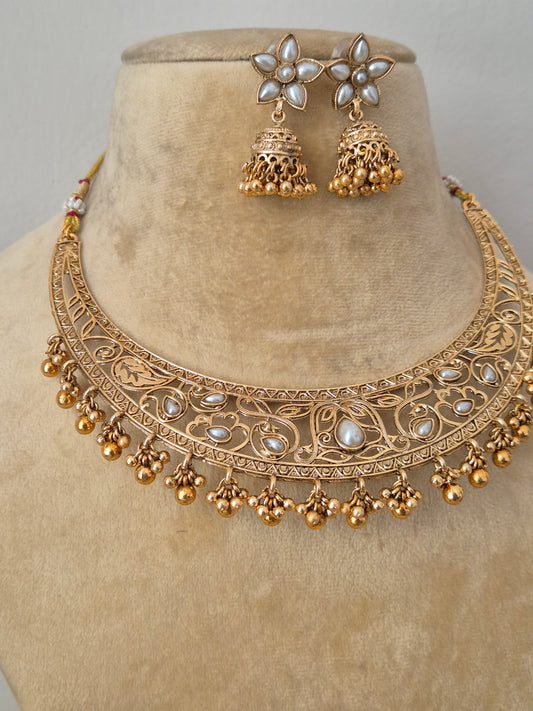 Traditional Indian antique-finish brass necklace set showcasing elaborate floral engravings, white gemstone embellishments, and a structured collar silhouette with delicate gold pearl drops by naitri.in