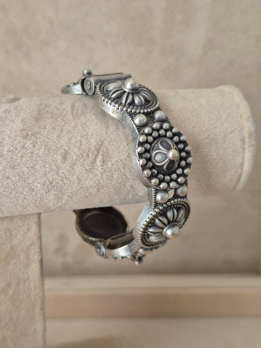 Close-up of Naitri Nafisa premium silver oxidized bangle bracelet with traditional Indian style textured leaf and flower metalwork.