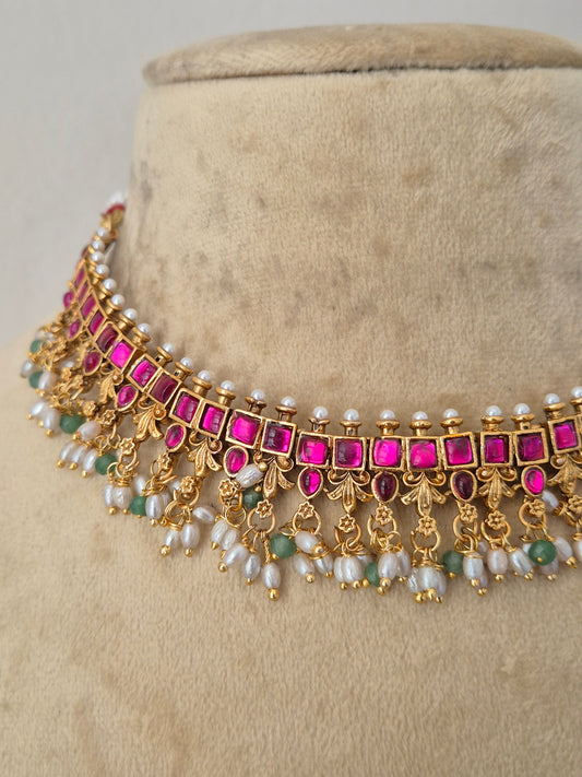 Gold-plated choker necklace with bright pink rectangular stones, white pearl-like beads, and small green stone accents, by naitri.in
