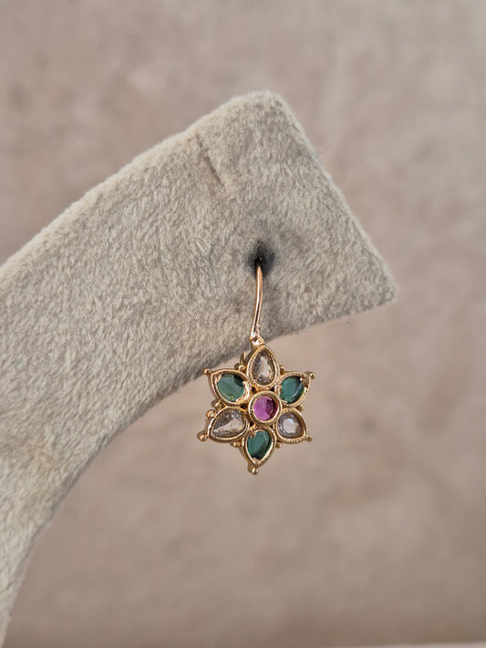 Pair of brass alloy stud earrings featuring a central cluster of vibrant ruby and green stones arranged in a floral motif by naitri.in