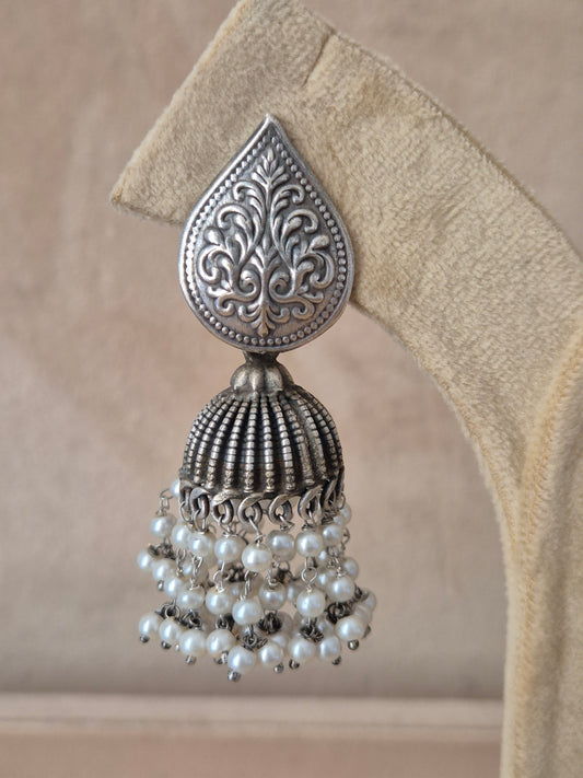 Modern Indian aesthetic silver-plated statement earrings with intricate metal work and hanging pearl accents by naitri.in