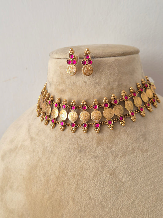 Modern Indian imitation jewelry set featuring an intricate golden brass alloy coin choker necklace with ruby-red gemstone accents, by naitri.in