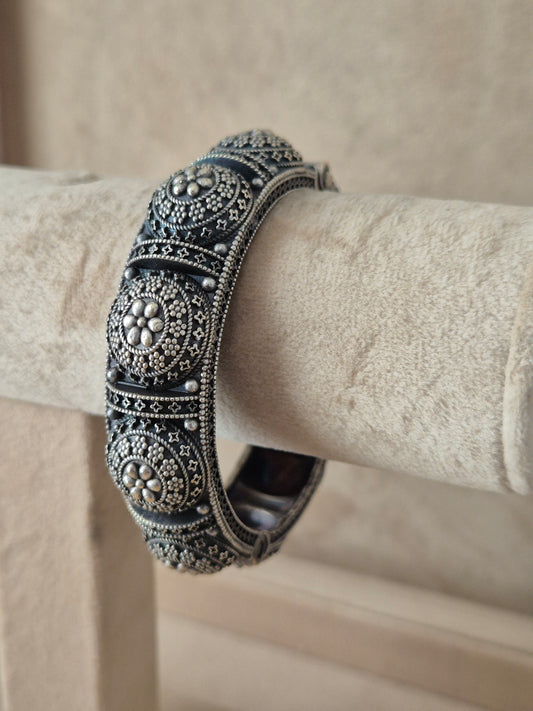 Close-up of Naitri Shilpa premium silver oxidized bangle bracelet featuring a central flower motif and detailed traditional metalwork by naitri.in