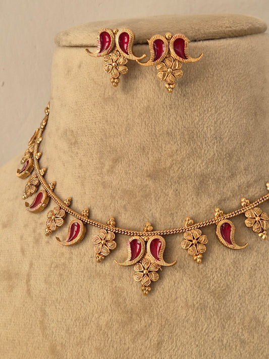 Gold-toned traditional Indian jewelry set featuring a floral garland necklace and matching earrings, embellished with red enamel details, by naitri.in