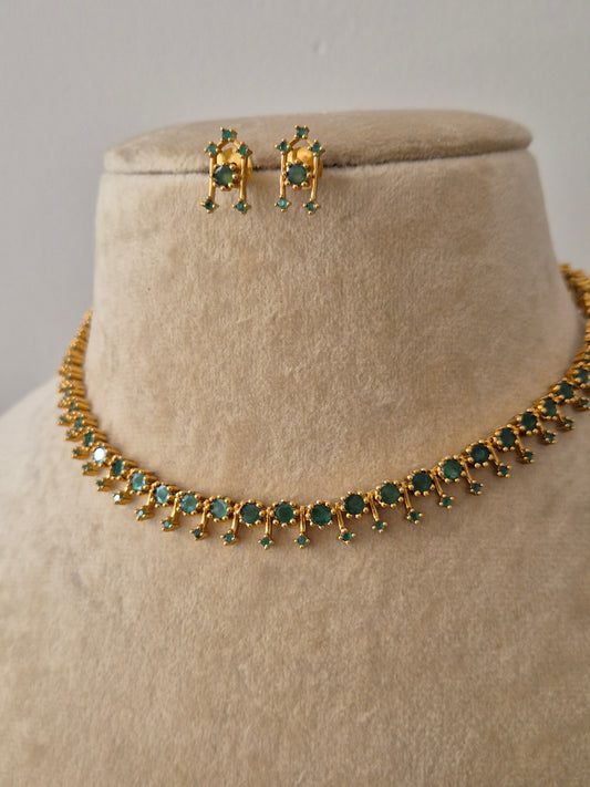 Handcrafted jewelry set in brass alloy with a polished golden finish and vibrant emerald-green stone accents by naitri.in