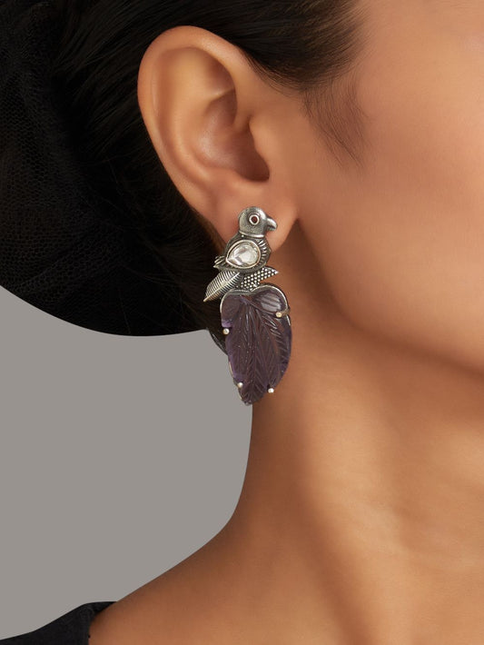 Purple stud earrings with stonework, displayed on a jewelry stand