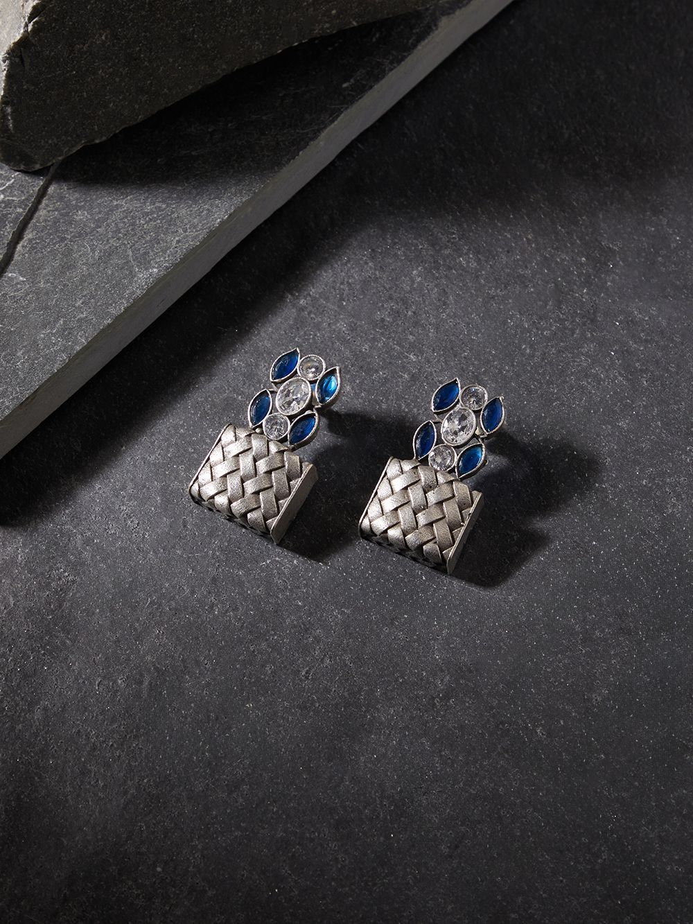 Silver drop earrings in brass and stone, simple background