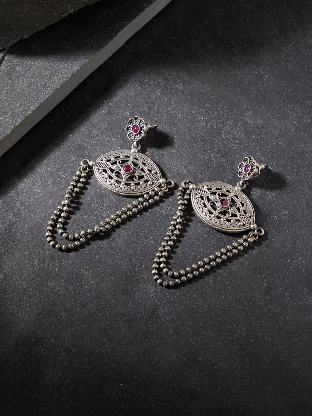 Silver-tone, traditional brass stud earrings shown on dark background