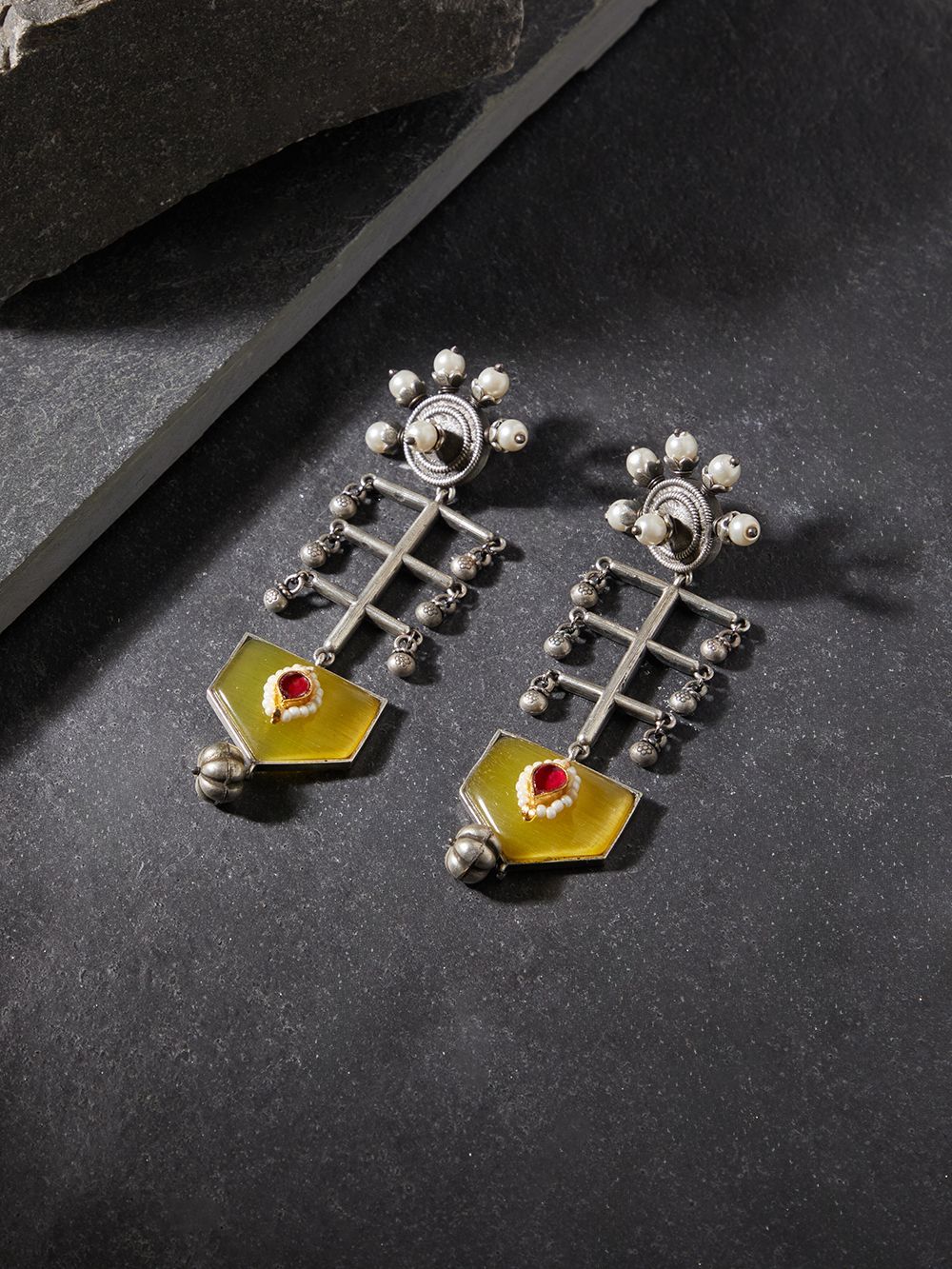 Yellow brass dangle earrings with stonework on neutral display