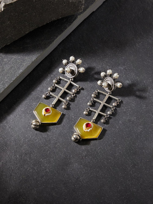 Yellow brass dangle earrings with stonework on neutral display