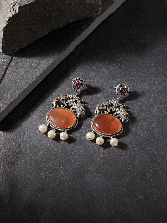 Red and silver dangle earrings, Rani by Naitri, stone accents, on fabric background.