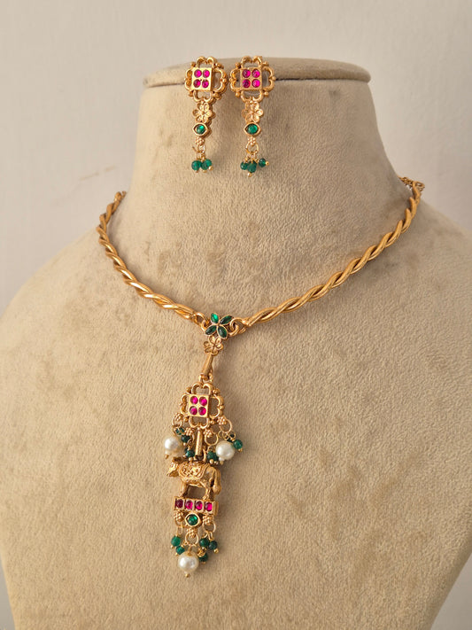 Traditional Indian Gold-Tone Pendant Set showcasing artisanal craftsmanship with vibrant ruby and emerald stone details, a polished gold finish, and matching earrings designed for ethnic festive wear by Naitri.in