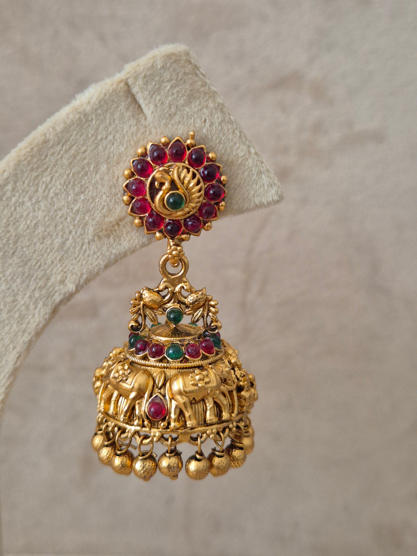 Gold earrings with red gemstones and elephant detailing and Handcrafted brass alloy with red and green stones and a polished golden finish.