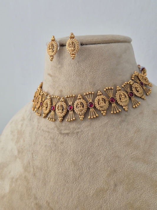 Handcrafted brass alloy ethnic necklace featuring intricate traditional motifs, red gemstone accents, and matching stud earrings by Naitri.in