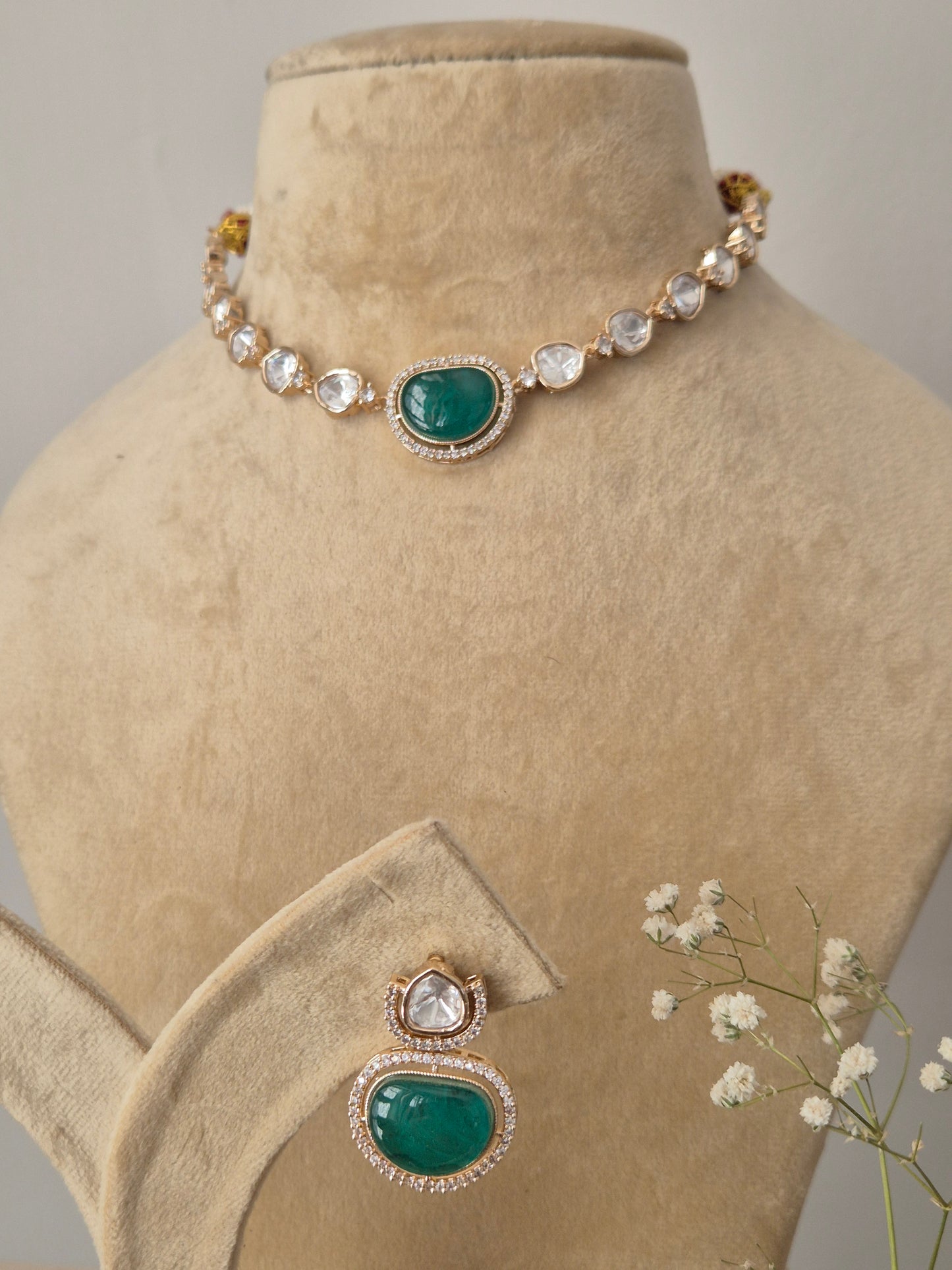 Close-up of a handcrafted necklace and earring set featuring emerald-colored stones and white AD crystals by naitri.in
