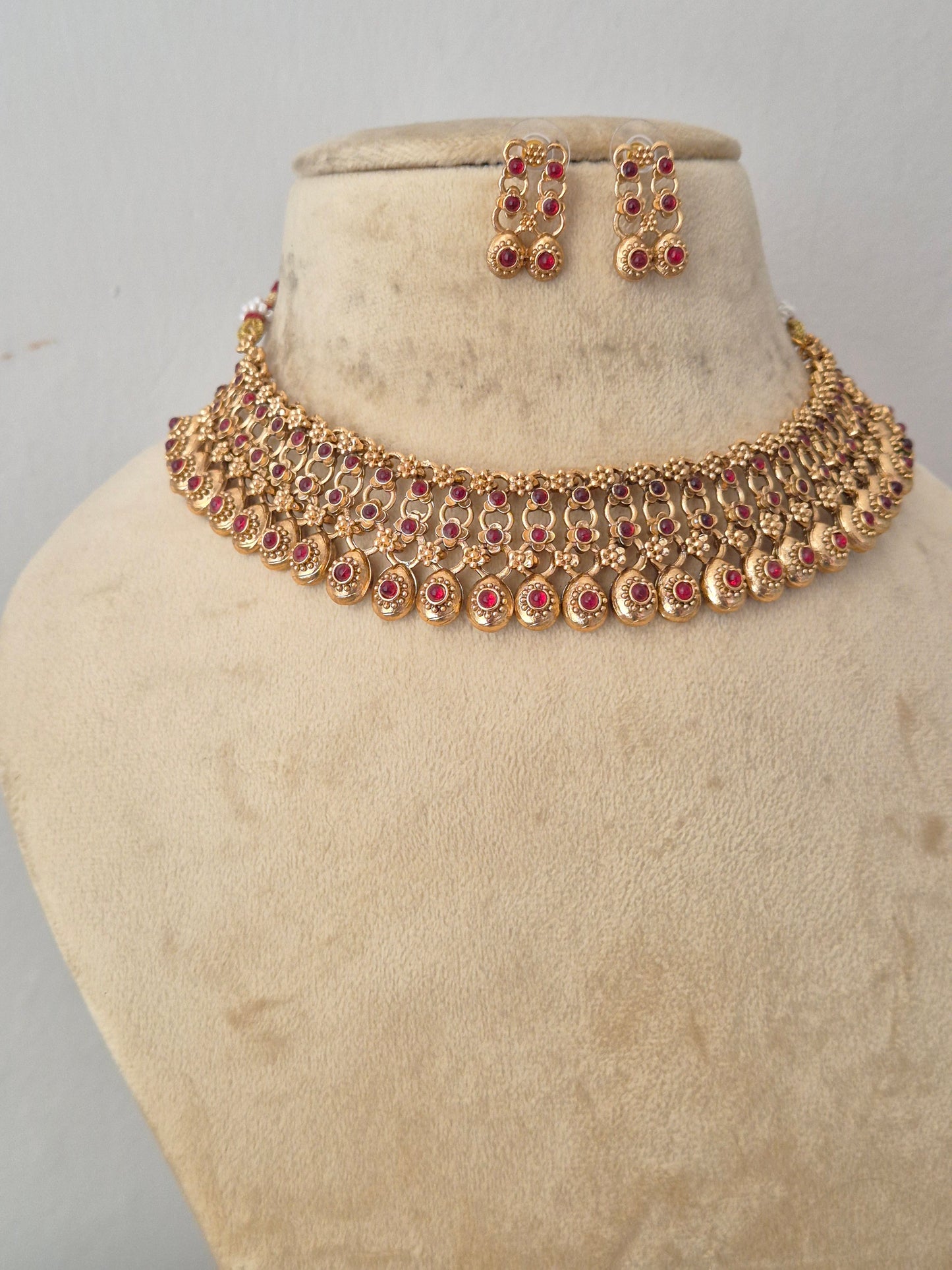 Gold-toned traditional necklace and matching earrings featuring a finely crafted brass alloy gold-plated choker and matching earrings for festive wear by naitri.in