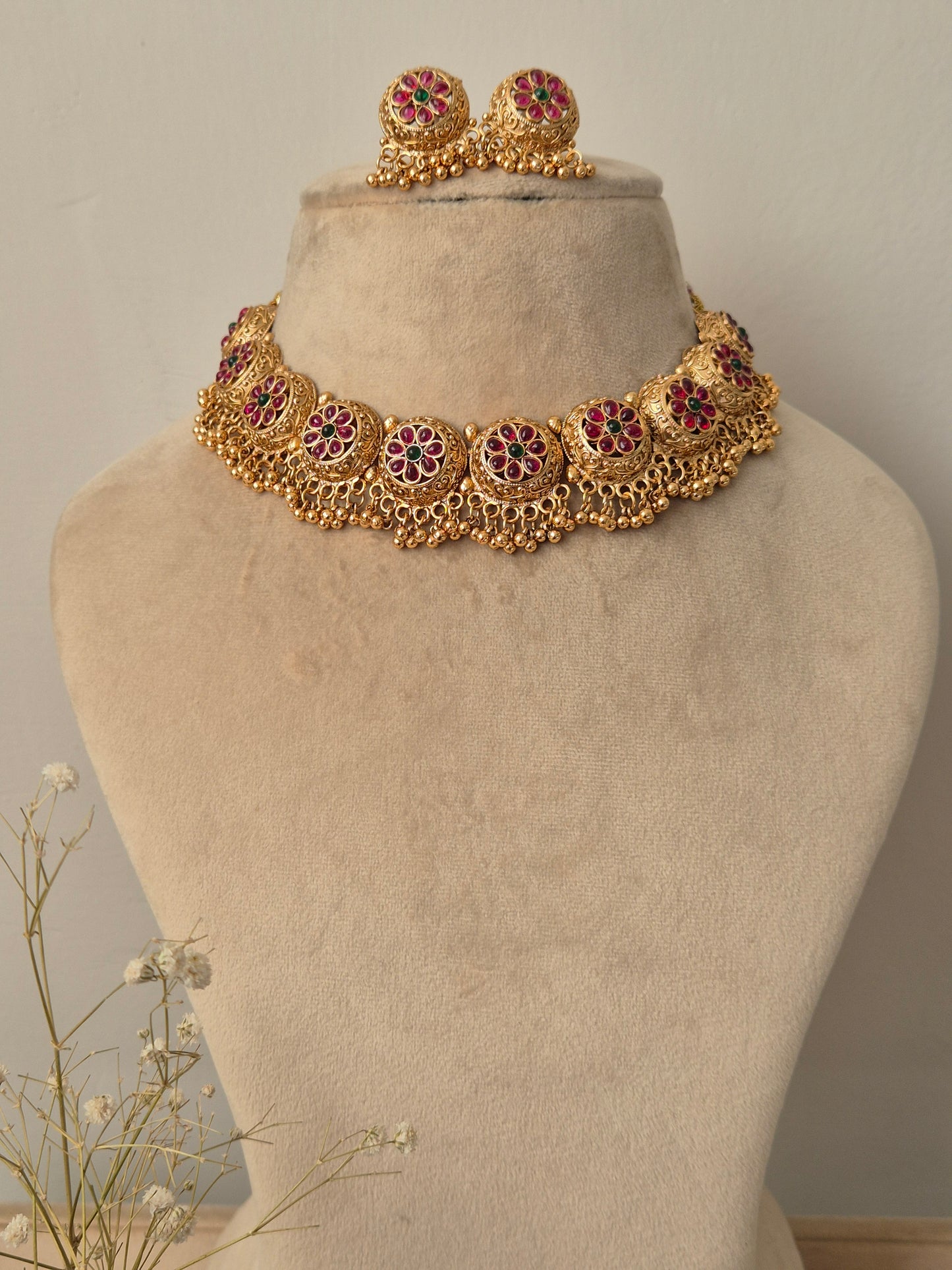 Floral gold necklace adorned with side design like bunches and green red studded flower charms by naitri.in