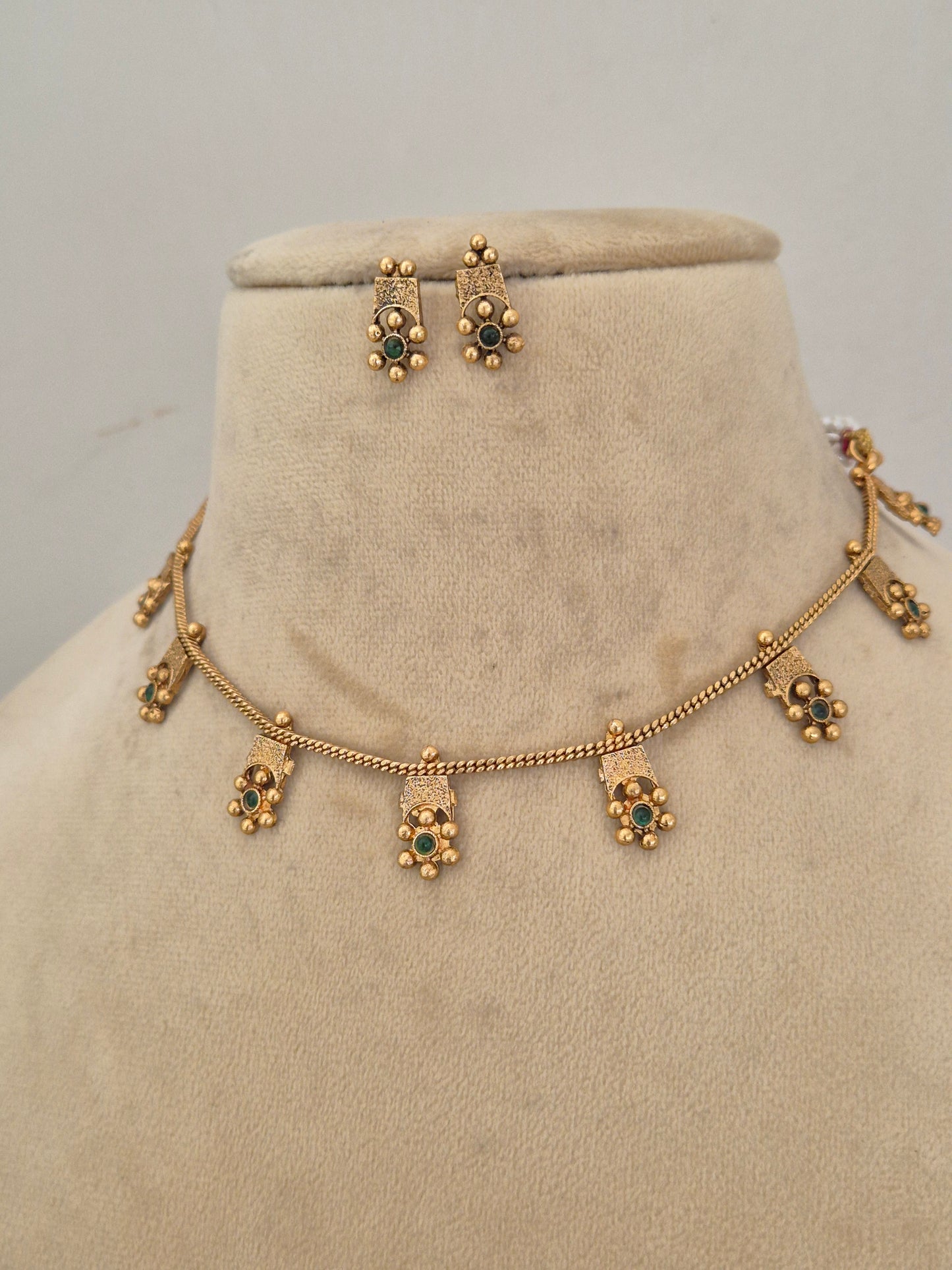 Quhu Necklace Set by Naitri featuring an ethnic gold-plated choker with green stone floral motifs for festive wear by naitri.in