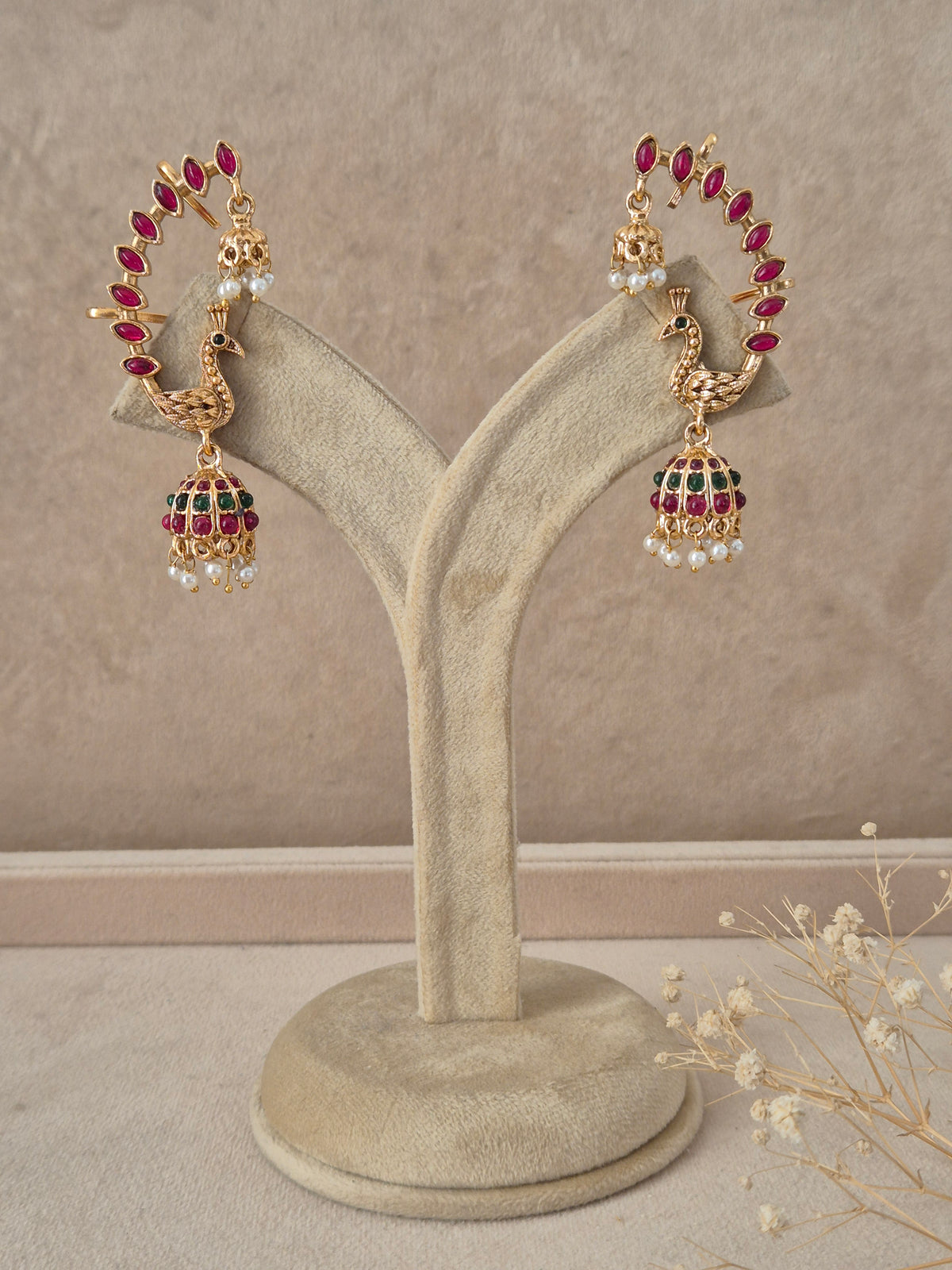 Gold-plated peacock stone and pearl jhumka earrings featuring a curved hoop studded with ruby-red stones leading to a bell-shaped dome with pearl drops by naitri.in