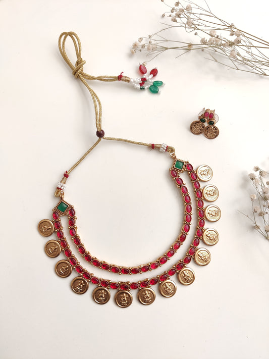 A necklace set with gold- adorned with red gemstones and coin-shaped embellishments by Naitri