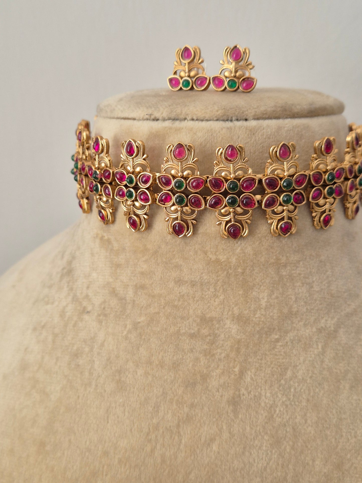 Gold-polished wide ethnic collar with red and green kemp stone embellishments and matching stud earrings from the Golden Ethnic Jewellery line by naitri.in