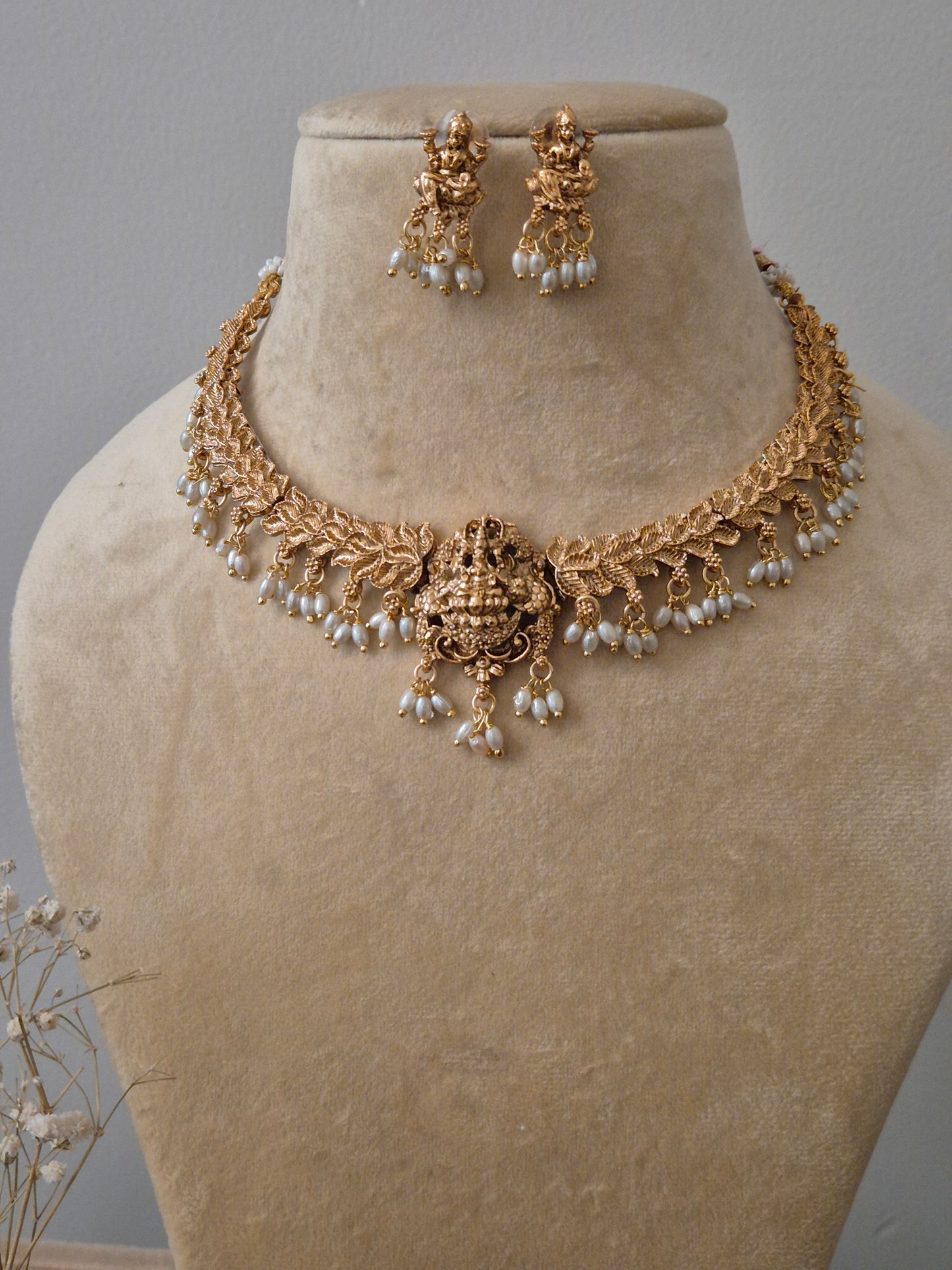 Handcrafted ethnic temple jewelry set in gold brass alloy with goddess engraving and white bead embellishments, perfect for festive or bridal wear by naitri.in