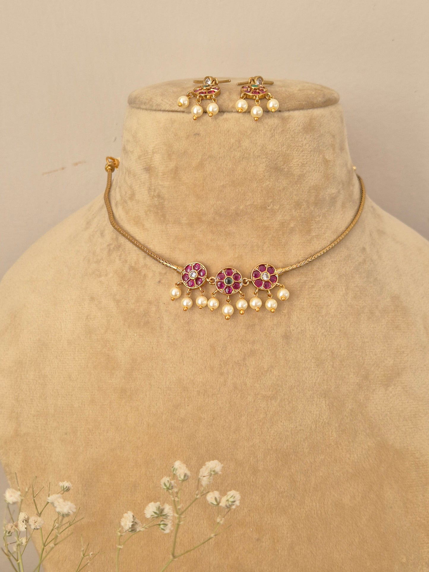 Handcrafted gold choker necklace and matching drop earrings featuring pink and green floral stones with seed pearl fringes by naitri.in