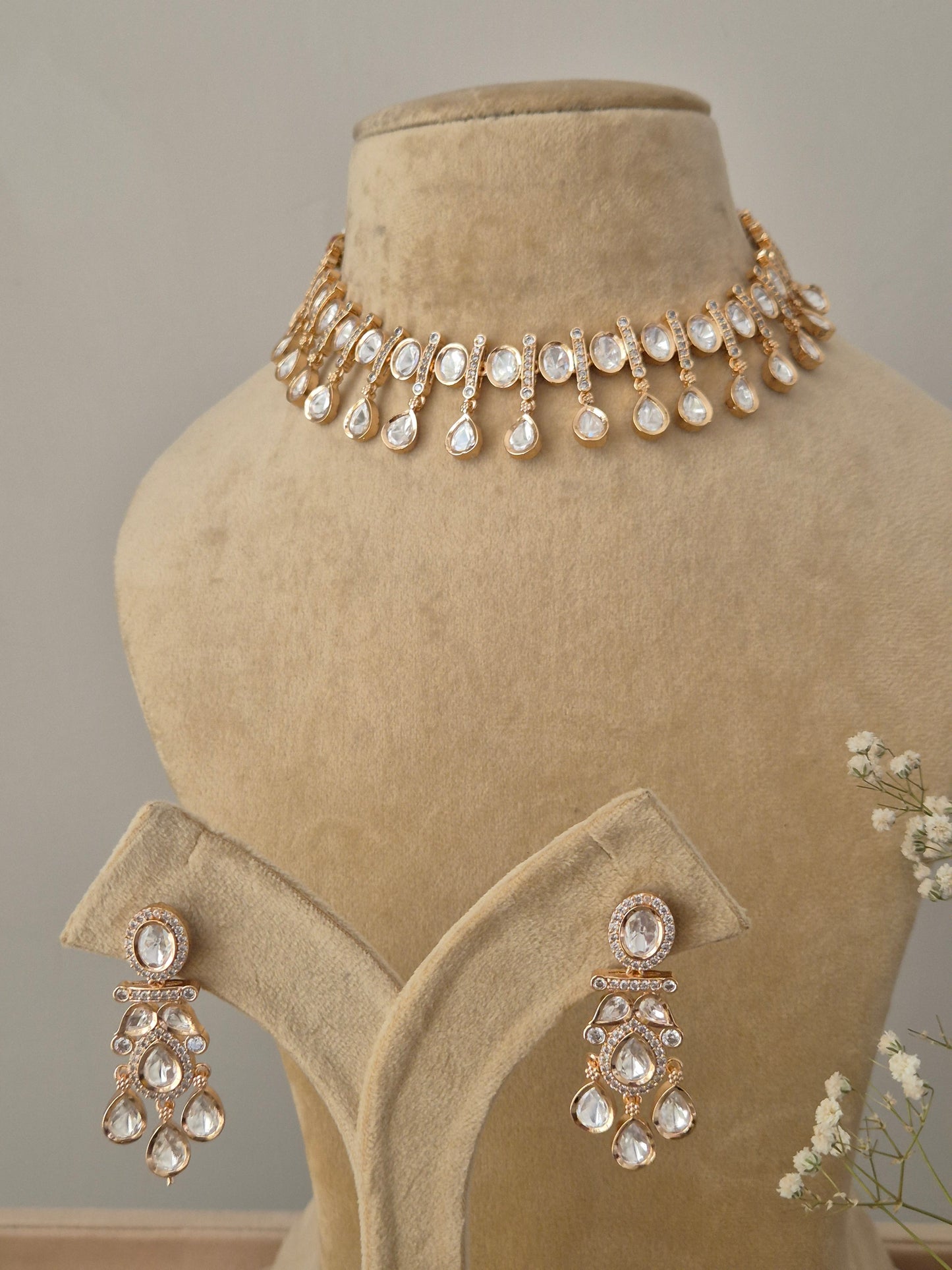 Traditional yet modern Indian Victoria necklace set with dangling American Diamond stones, drop earrings with a floral stud and teardrop crystal, displayed alongside the coordinating stately choker necklace by naitri.in