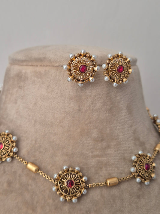 Ornate gold necklace with red stones and pearl-like beads all side of the round flower pearls unique and minimal designed earring and pendant having same design by naitri.in