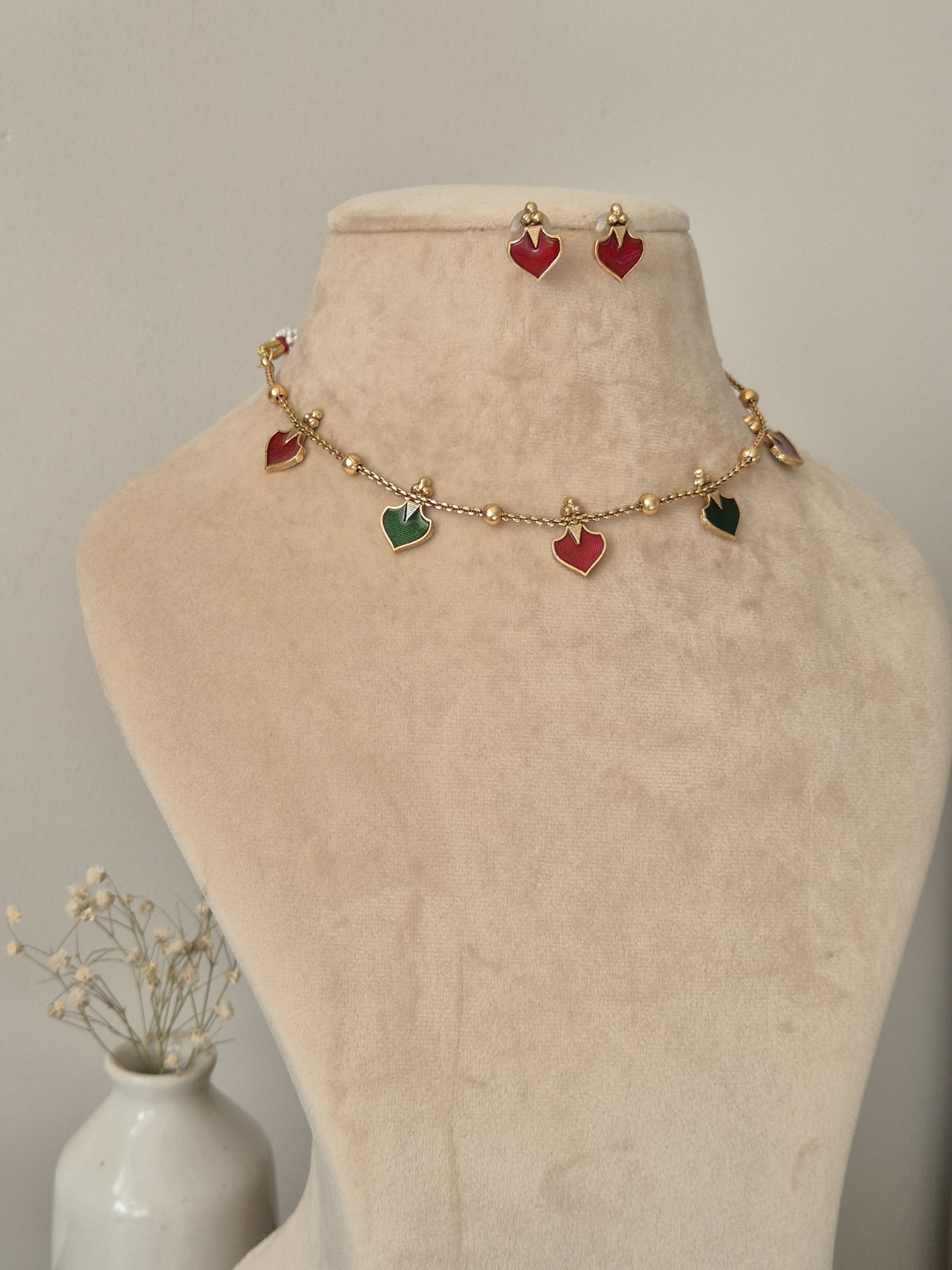 Luxurious temple necklace set with gold, red, and green highlights, draped to display fine artisan work
