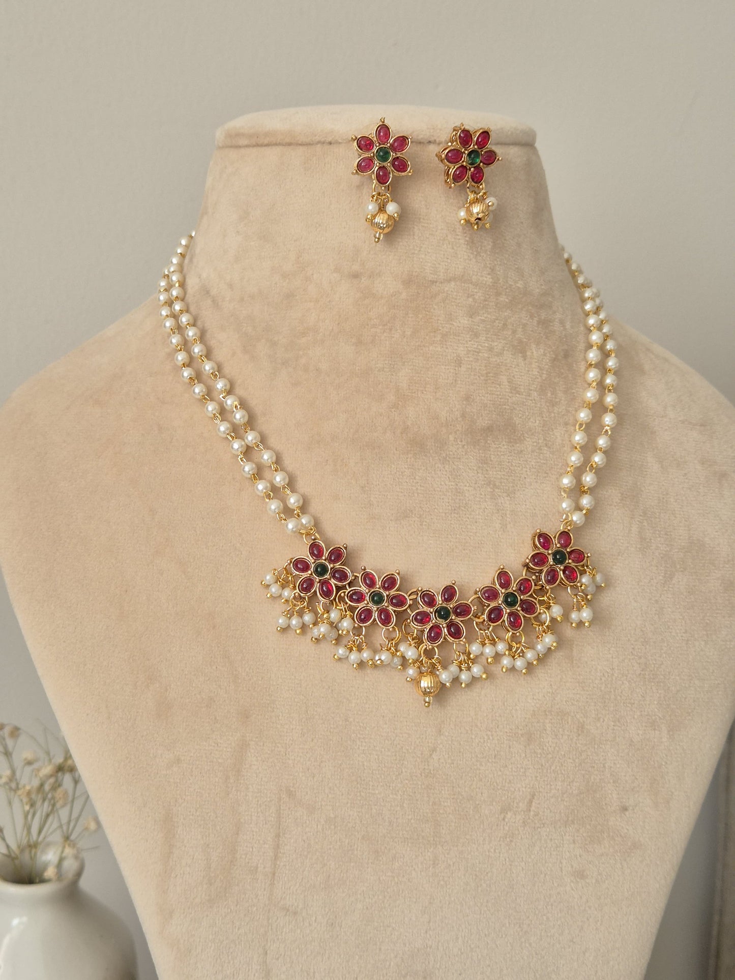 Artistic shot of temple necklace set featuring gold, green, and red embellishments and intricate metalwork