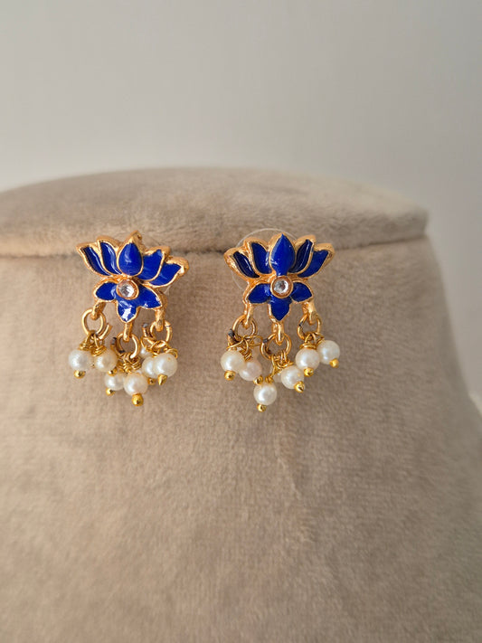 Pair of gold earrings with blue petals and leaves and white pearls a small stone in the middle minimal and aesthetic design by naitri.in