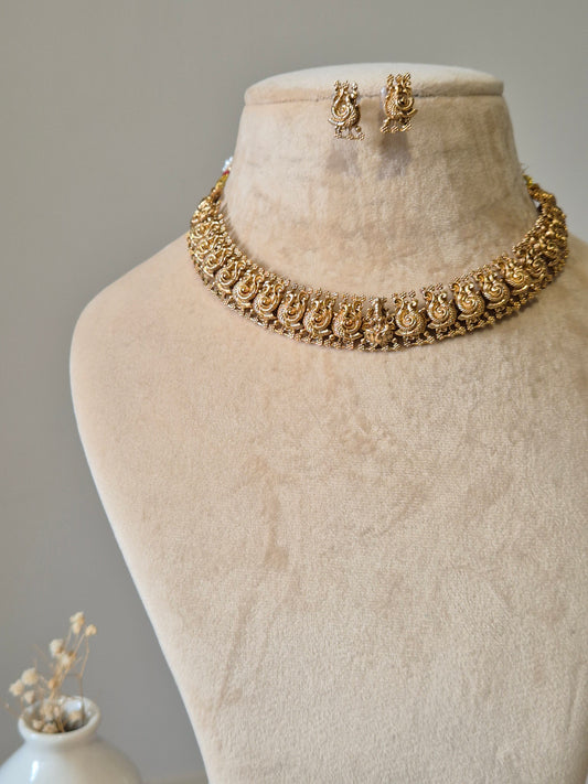 Gold necklace set, Bhaviki by Naitri, ethnic design displayed on fabric.