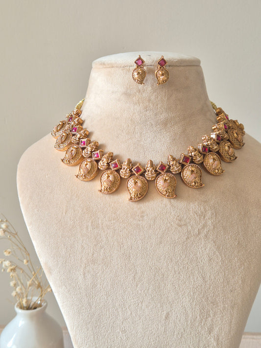 Gold necklace set with matching earrings, Nimai by Naitri, displayed on fabric.