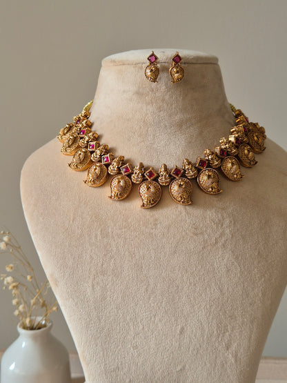 Gold necklace set with matching earrings, Nimai by Naitri, displayed on fabric.