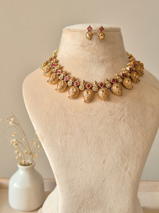 Gold necklace set with matching earrings, Nimai by Naitri, displayed on fabric.