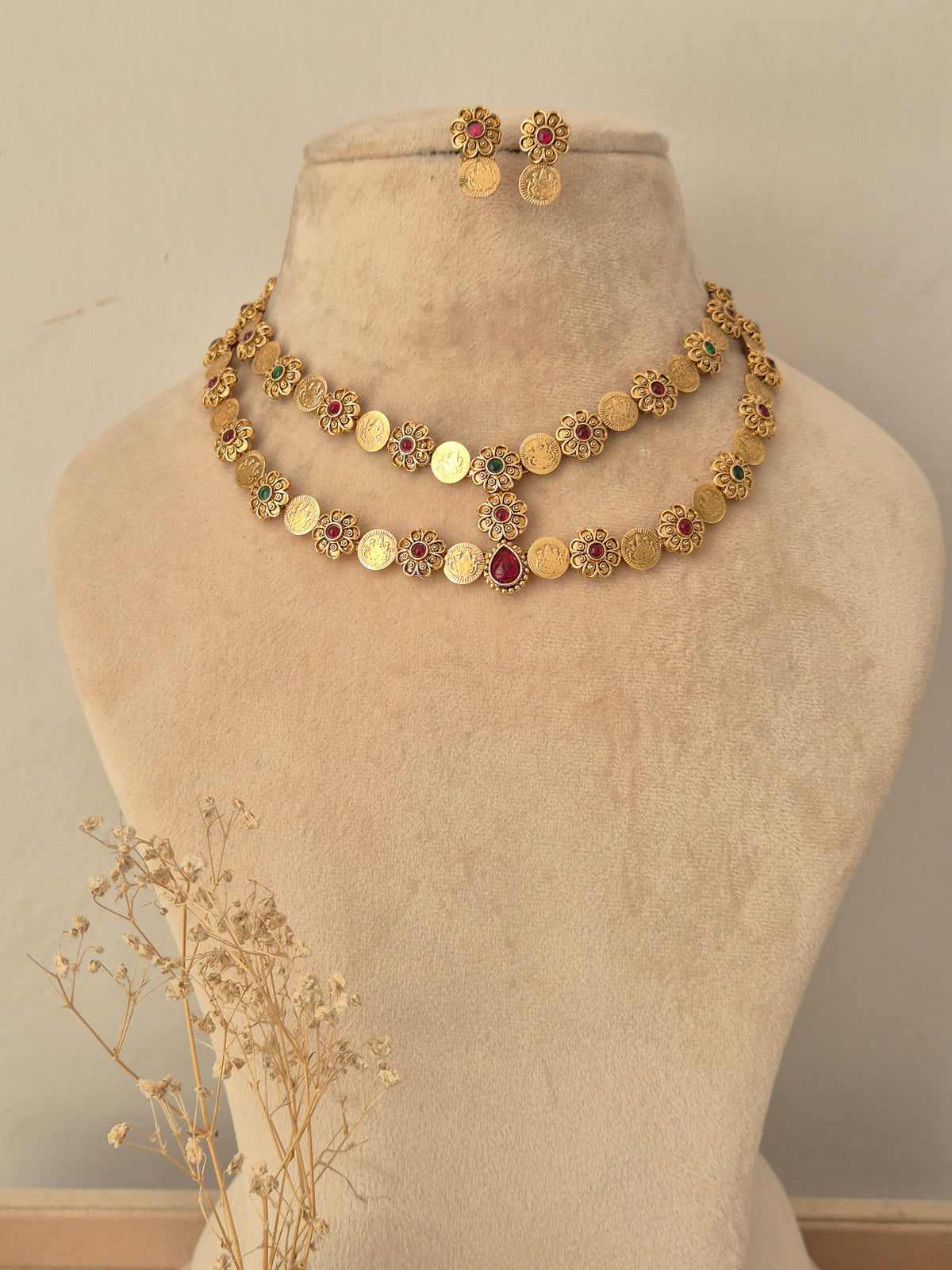 Yamya gold-plated double-layer coin necklace set with red and green stone accents, displayed on a mannequin bust with matching earrings.