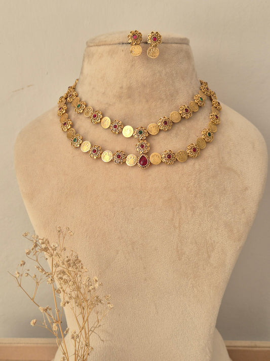 Yamya gold-plated double-layer coin necklace set with red and green stone accents, displayed on a mannequin bust with matching earrings.