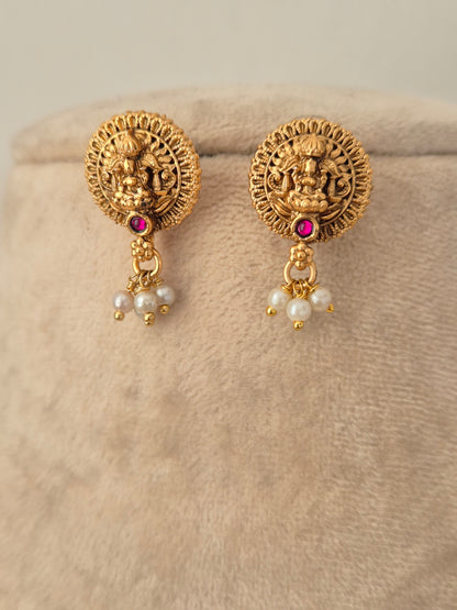 Gold-toned circular temple stud earrings with Goddess Laxmi motif, red stone centers, and dangling pearl drops from the Yamira necklace set.