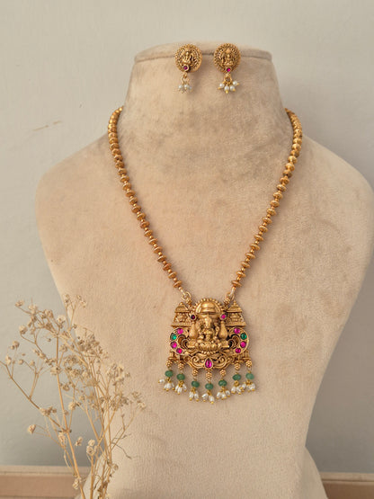 Yatishri gold-toned temple necklace set with Goddess Laxmi pendant, red and green stones, pearl drops, and matching stud earrings