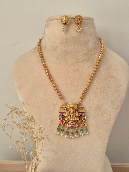 Yatishri gold-toned temple necklace set with Goddess Laxmi pendant, red and green stones, pearl drops, and matching stud earrings
