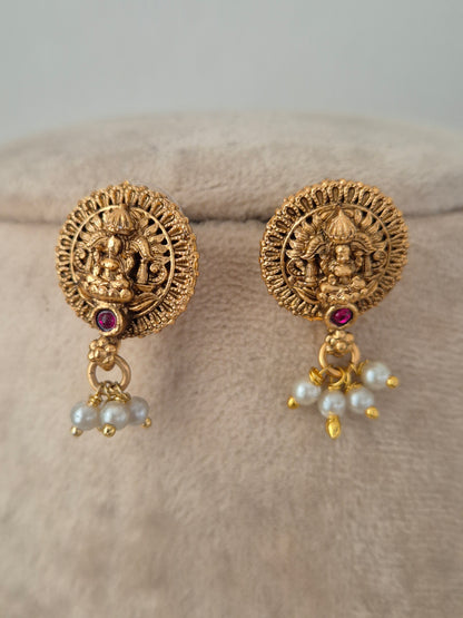 Circular gold-toned temple stud earrings featuring Goddess Laxmi motif, red stone center, and dangling pearl drops from the Yatishri set