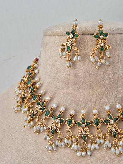 Close-up of Ladli gold-toned choker necklace with green floral stone motifs and hanging pearl clusters, paired with matching drop earrings
