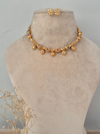 Lekhani gold-toned necklace set with red and green bead accents, hanging gold ball drops, and matching floral stud earrings