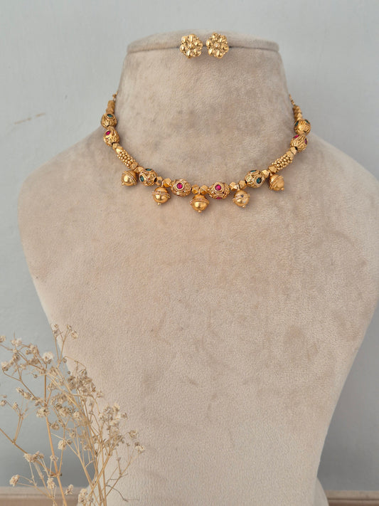 Lekhani gold-toned necklace set with red and green bead accents, hanging gold ball drops, and matching floral stud earrings
