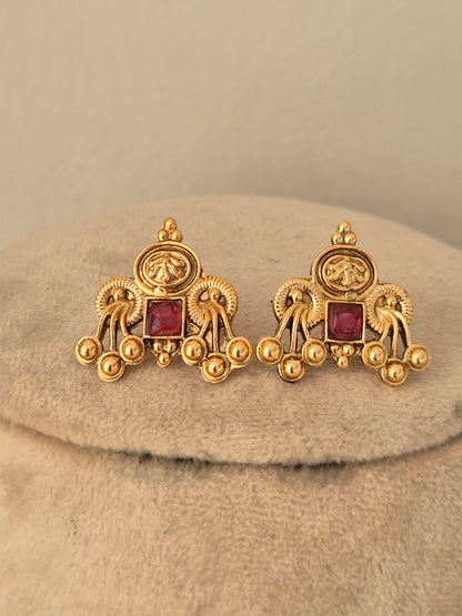 Matching gold-finish brass alloy stud earrings featuring square red stone centers and intricate traditional bead accents