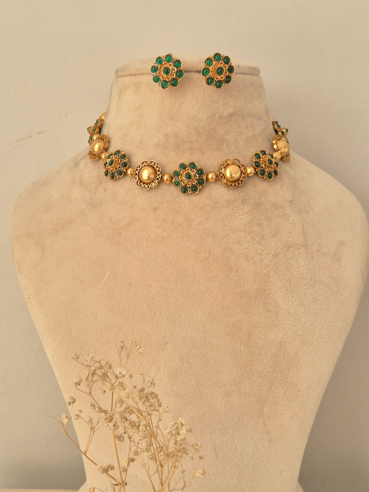 Gaurika gold-toned floral choker necklace set with green stone motifs and matching stud earrings